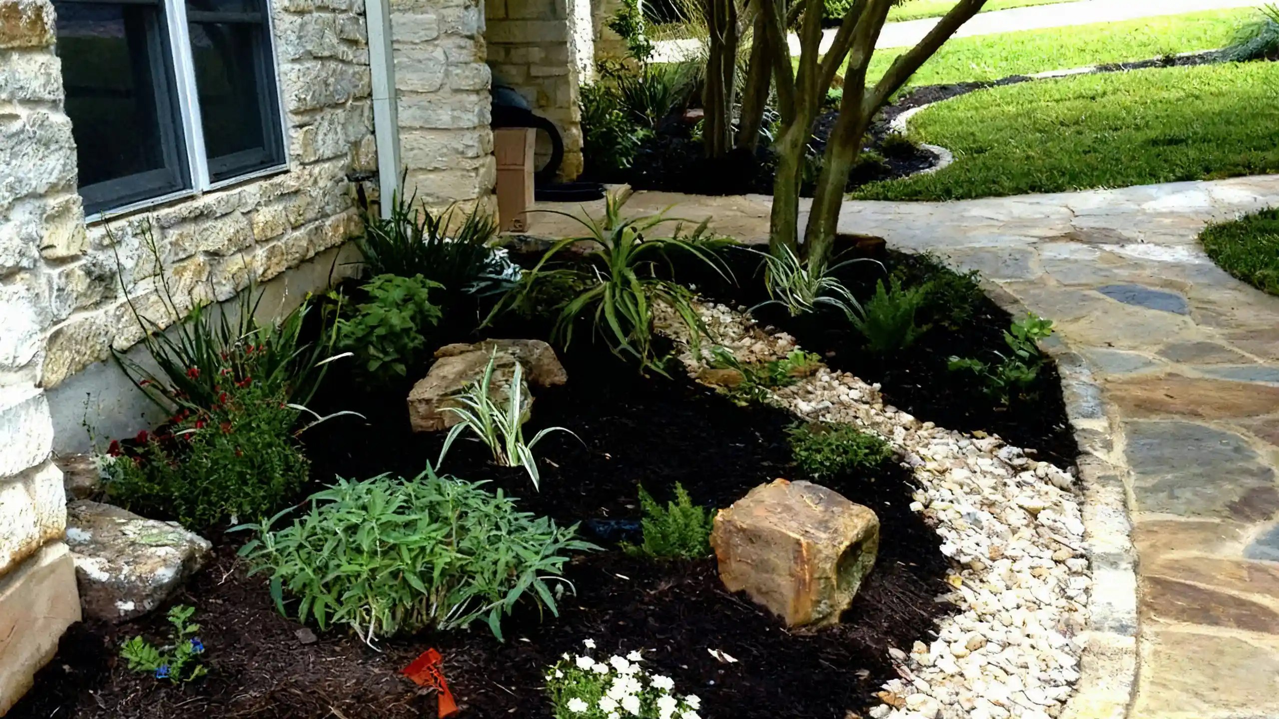 Foundation landscaping with native plants, boulders, and flagstone walkway