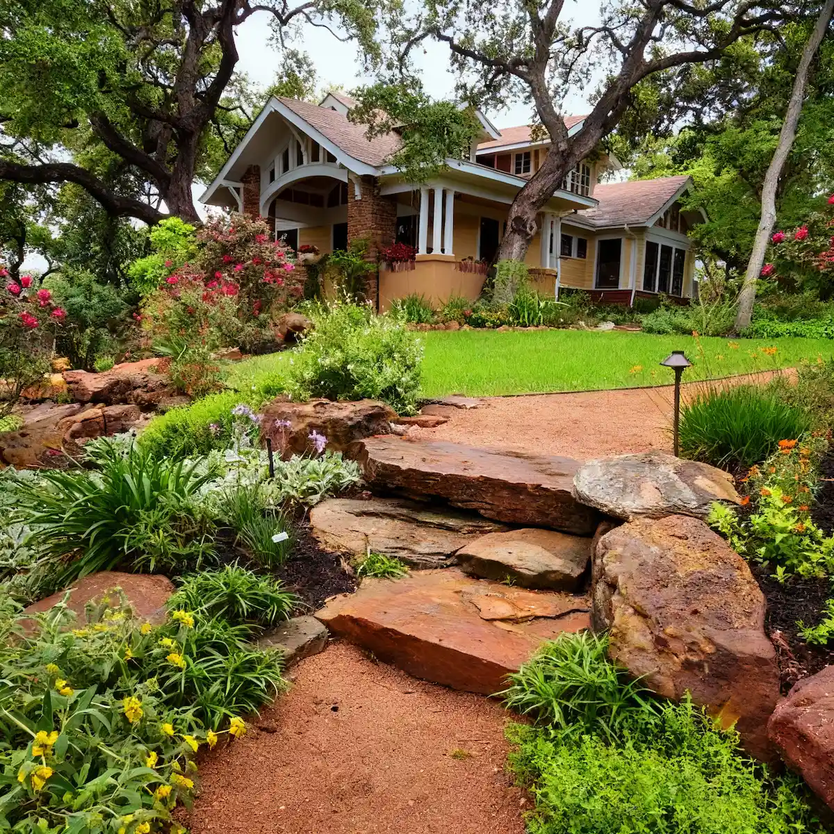 Stone pathway with native Texas plantings leading to craftsman-style home